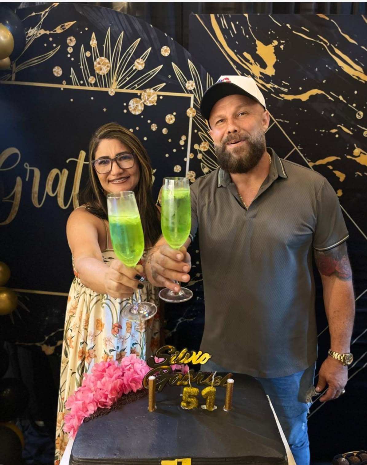 Aniversariantes brindando em frente ao painel decorado