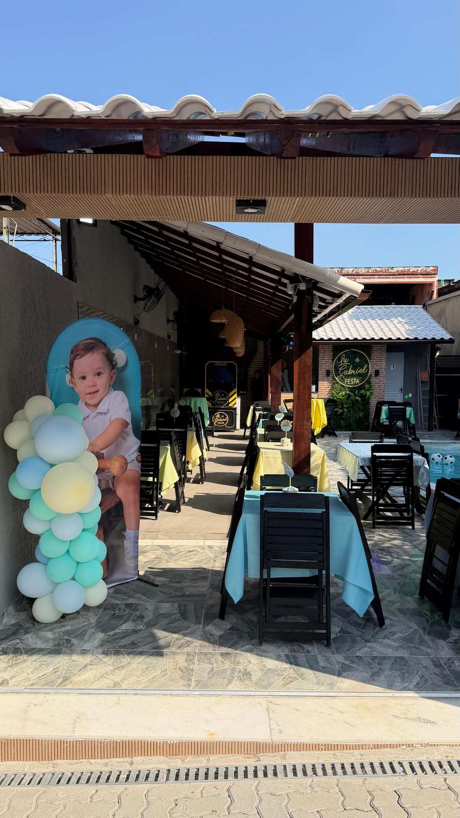 Mesas decoradas com toalhas na área coberta em dia de festa